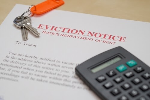 A calculator, property keys and eviction notice paper on a desk of a landlord who is calculating how much notice to give tenant