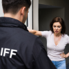 Man wearing 'Bailiff' jacket talking to a woman in the front doorway