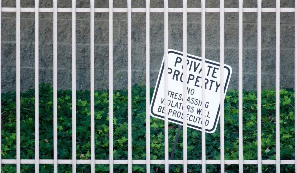 Fence with a sign reading 'Private property, no trespassing, violaters will be prosecuted'