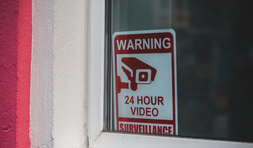 Property window with a sign that reads 'warning, 24 hour video surveillance'